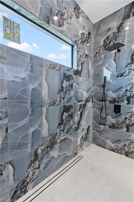 Walk-in shower with full-height patterned tile walls, a horizontal privacy window, a matte black rain shower head, and a linear floor drain