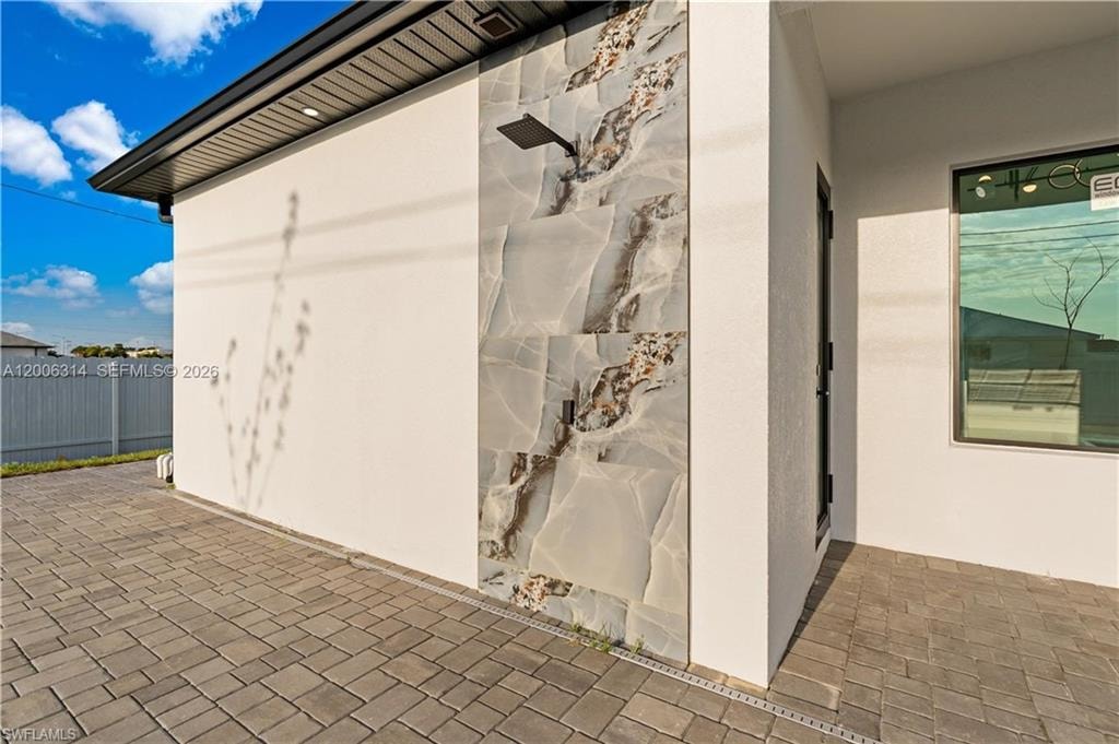 Exterior wall featuring large-format decorative stone paneling and a modern shower fixture