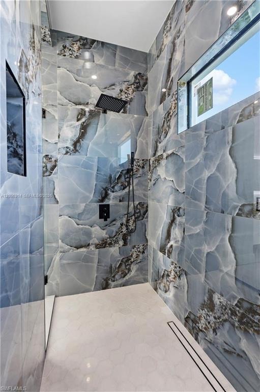 Walk-in shower featuring full-height porcelain tile walls with a blue and grey veining pattern