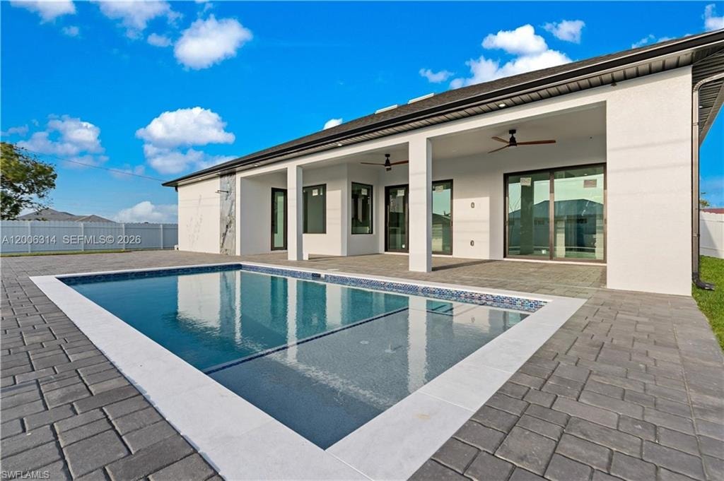 Rectangular swimming pool with a mosaic tile border, surrounded by dark grey paver decking