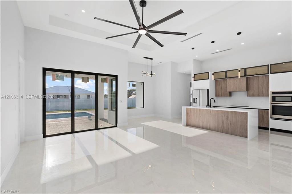 Open-concept living space featuring high ceilings, large format tile flooring, and a contemporary kitchen