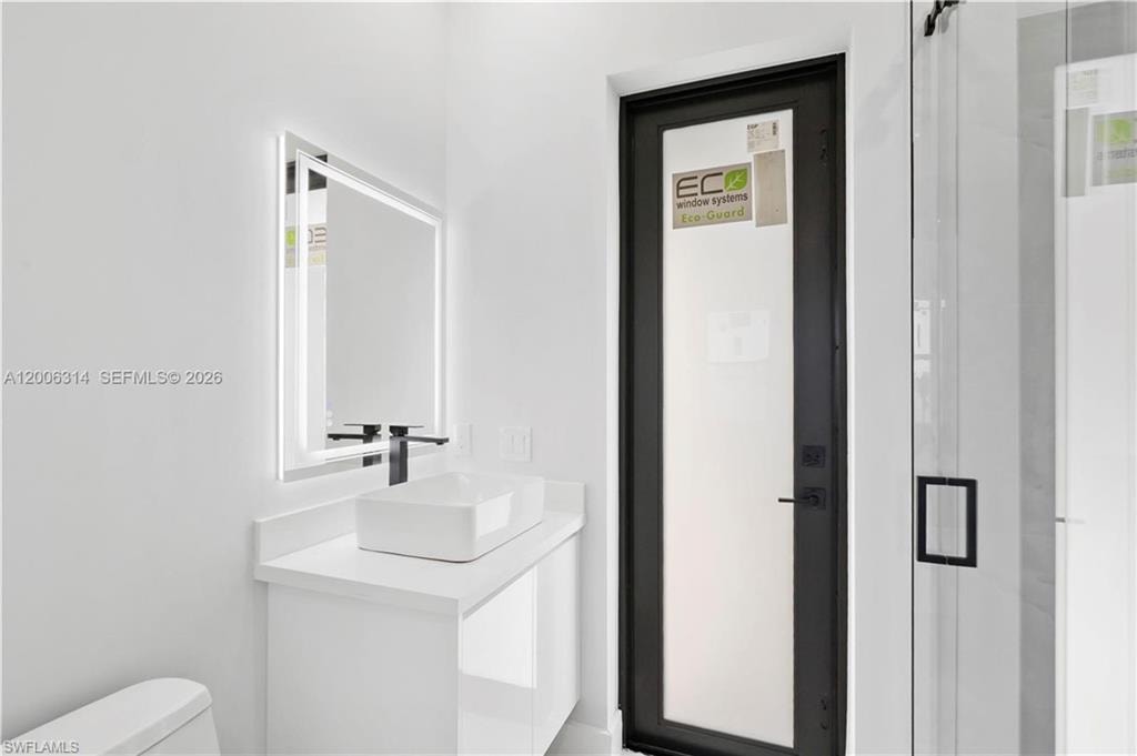 Modern vanity featuring a rectangular vessel sink, wall-mounted matte black faucet, and an illuminated mirror