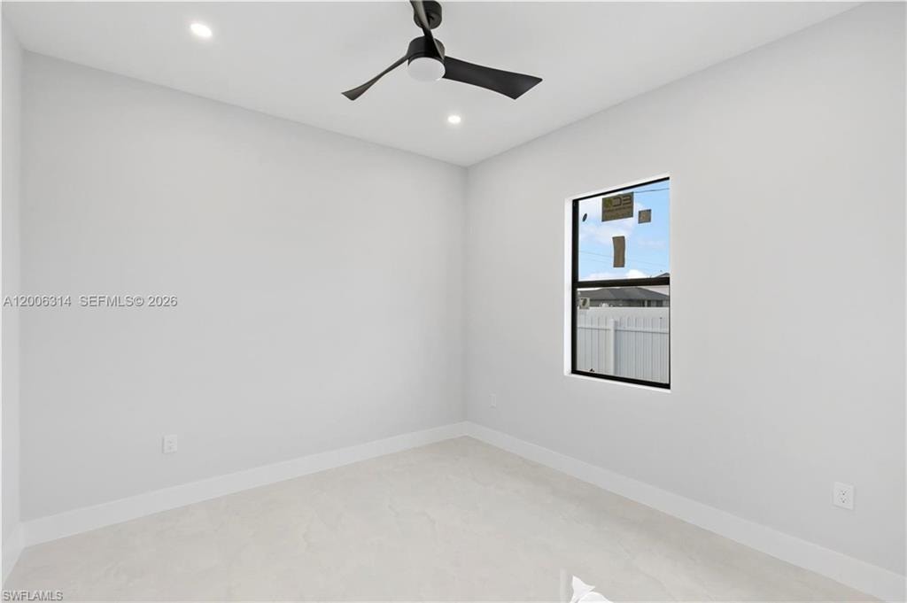 Room featuring light-toned flooring, crisp white walls, and a contemporary black ceiling fan with integrated lighting