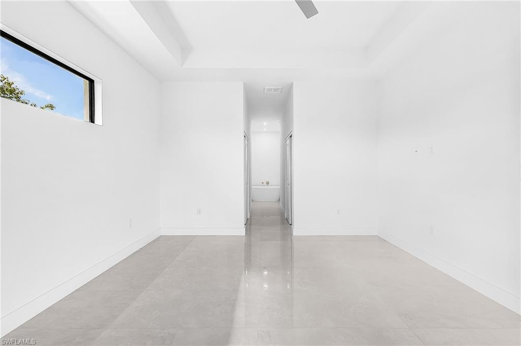 Spacious interior room featuring light-toned tile flooring and crisp white walls
