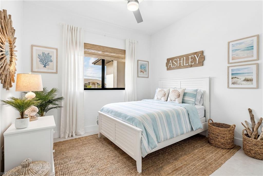 Bright bedroom featuring a single window with a woven shade, white sheer curtains, and a ceiling fan