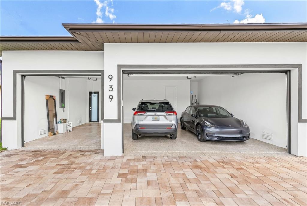 Modern exterior featuring a two-bay garage with contemporary gray trim, a durable paved driveway, and a secure side entry door