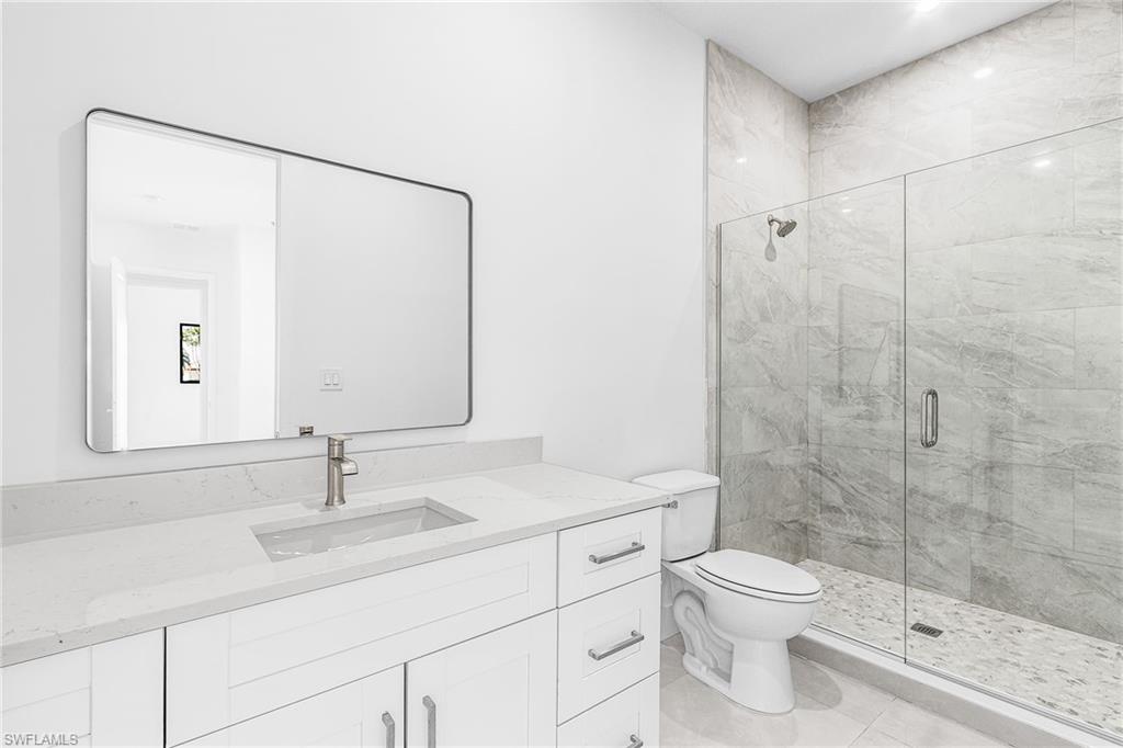 Modern bathroom featuring a glass-enclosed shower with gray tiled walls and flooring