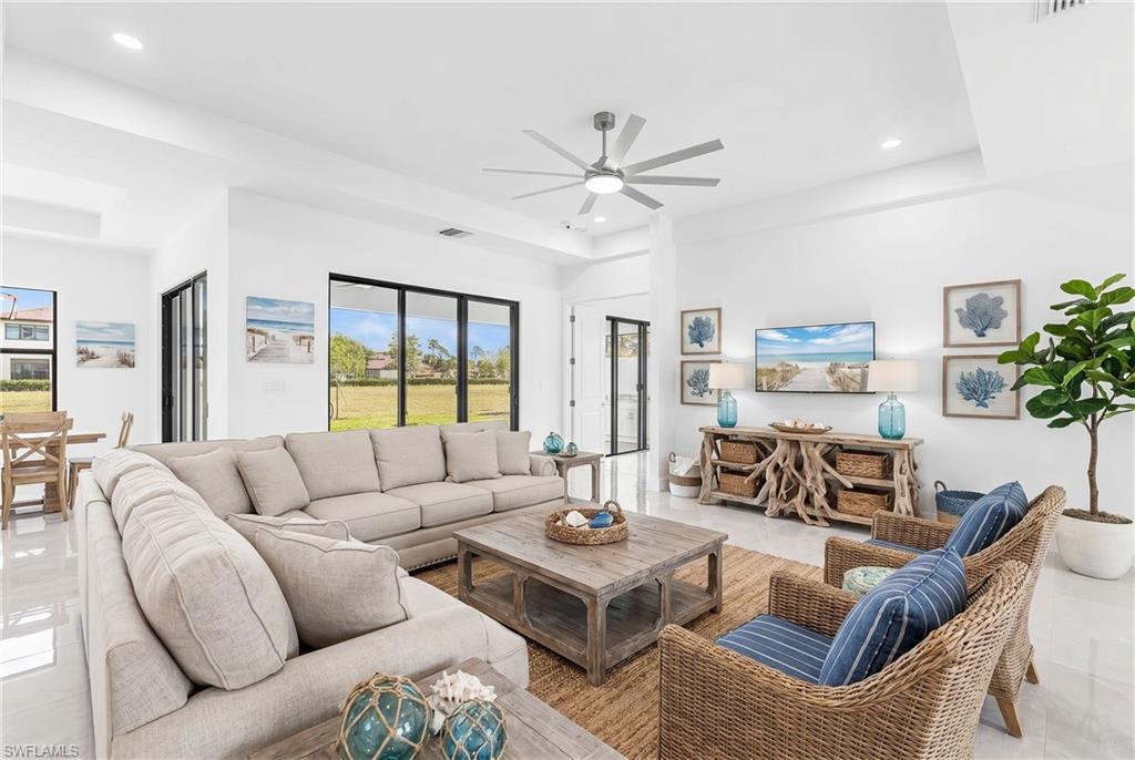 Spacious living area featuring polished tile flooring, recessed lighting, a modern ceiling fan, and large black-framed sliding glass doors opening to the exterior