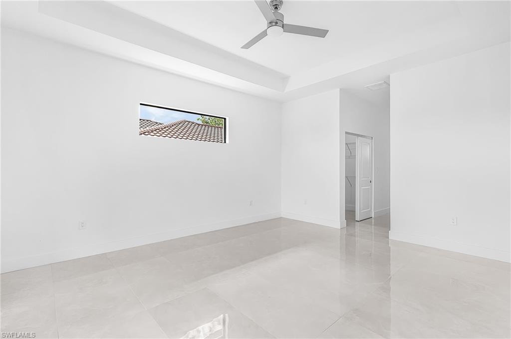 Spacious room featuring light-toned tile flooring, white walls, and a contemporary ceiling fan