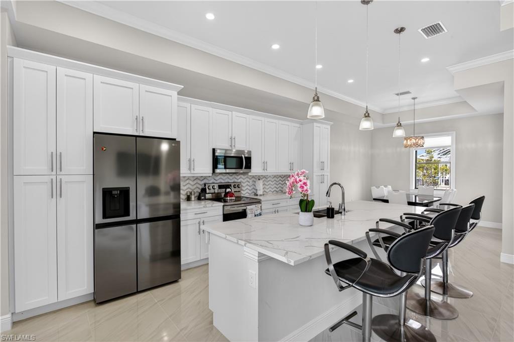 CHEF-INSPIRED KITCHEN featuring WHITE SHAKER CABINETRY, QUARTZ COUNTERTOPS, STAINLESS STEEL APPLIANCES, FULL TILE BACKSPLASH, WALK-IN PANTRY and an OVERSIZED CENTER ISLAND ideal for entertaining, casual dining or gathering with family and friends.