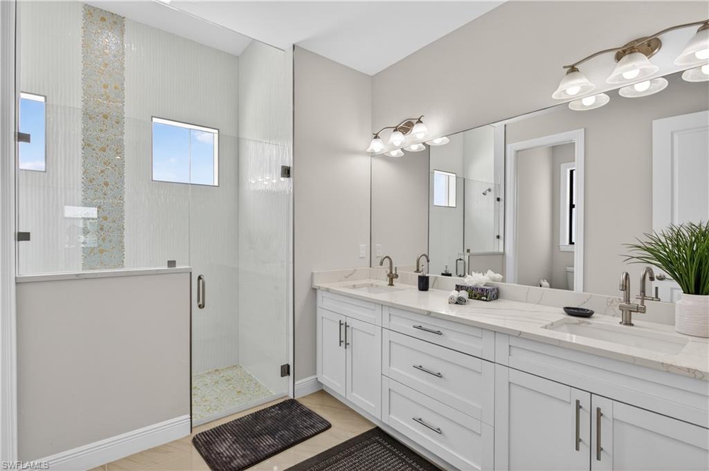 SPA-STYLE BATHROOM showcasing DUAL VANITIES, DESIGNER FINISHES and an oversized WALK-IN GLASS SHOWER with elegant tile detail.