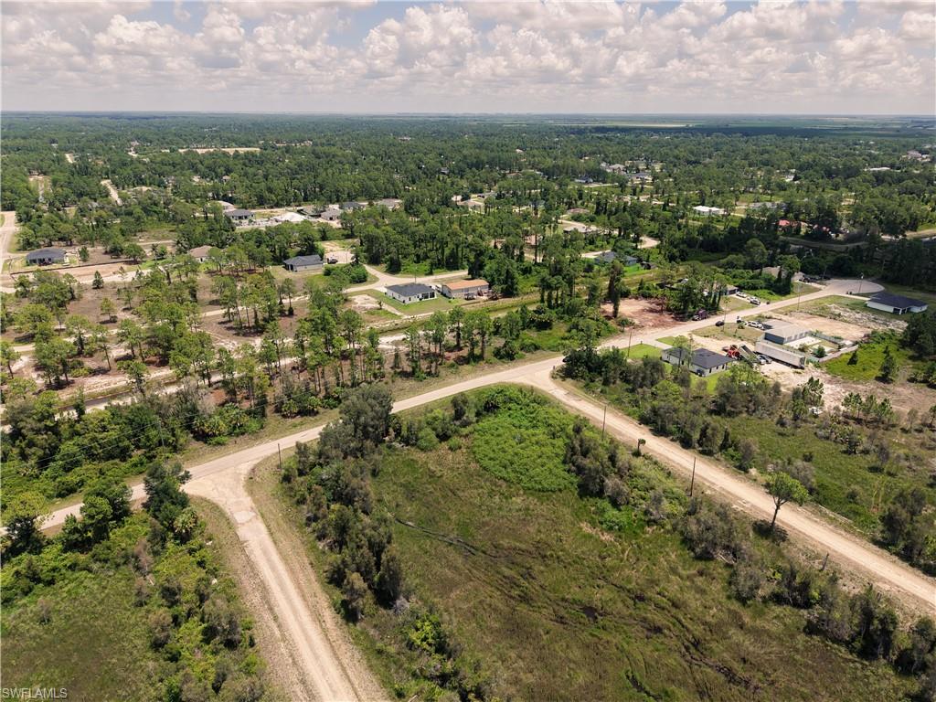Expansive aerial showcasing a landscape with scattered residential properties, mature trees, and unpaved roads