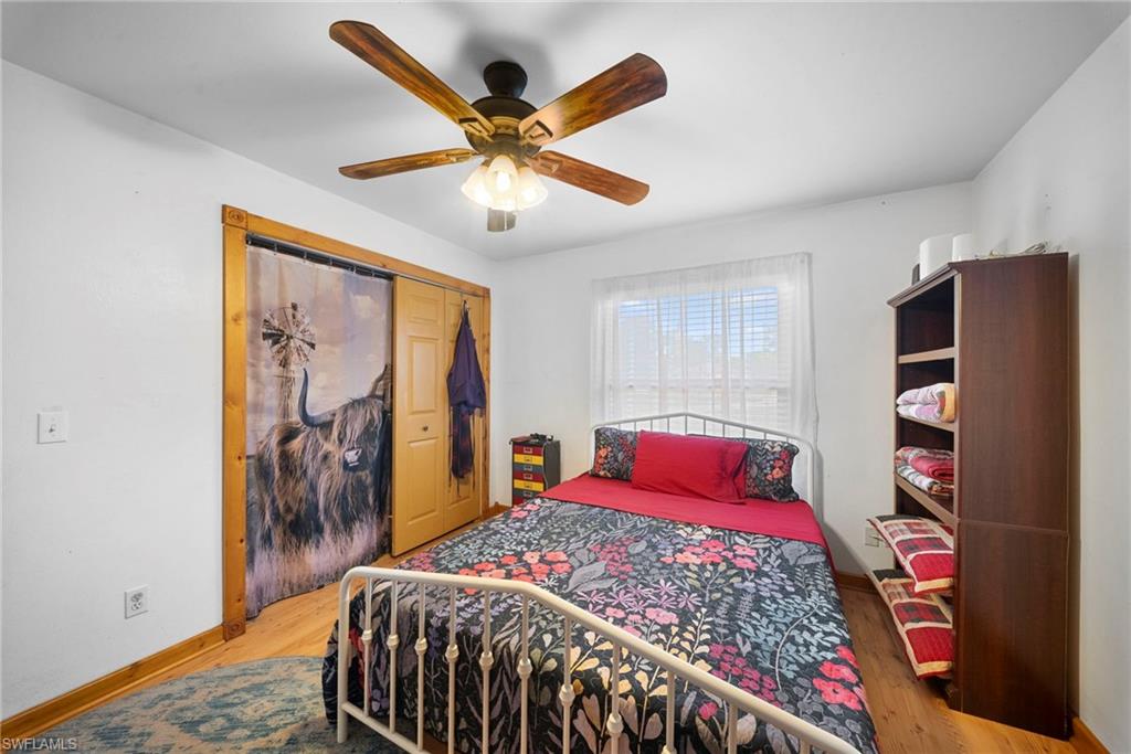 Bedroom featuring wood-finish flooring, a ceiling fan with light fixture, and a window with blinds