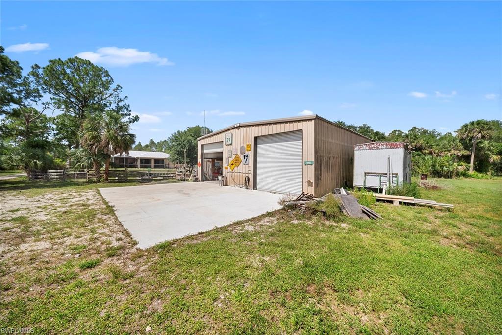 Metal-sided workshop with two roll-up doors, an open bay, and a concrete pad