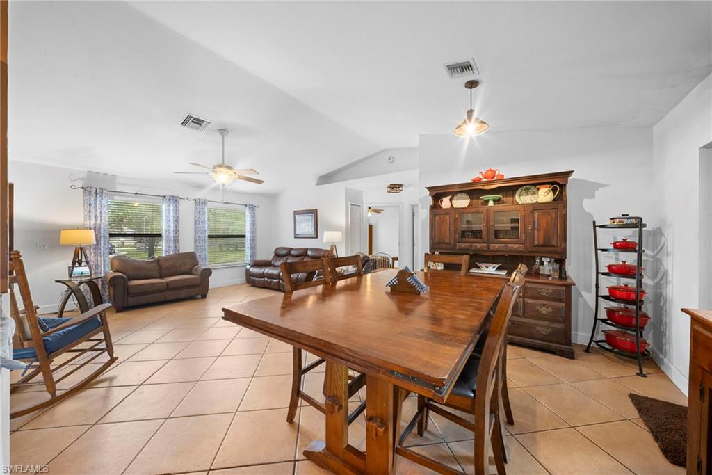 Open-concept living area featuring tile flooring, vaulted ceilings, and natural light from multiple windows