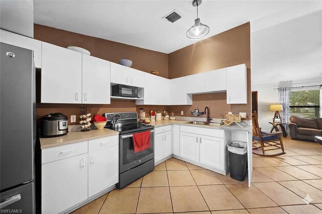 Kitchen featuring white cabinetry, light countertops, and a black appliance suite