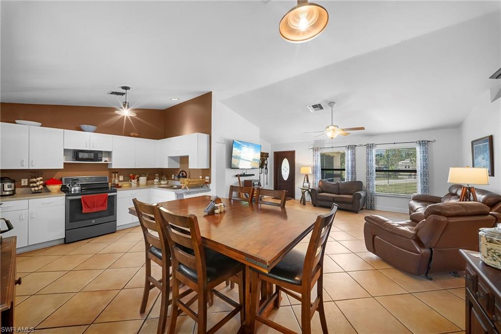 Open-concept living area featuring a kitchen with white cabinetry, a built-in microwave, and a black range