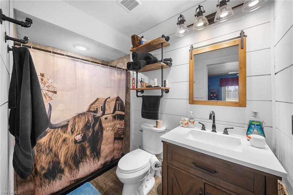 Bathroom featuring shiplap wall paneling and wood-finish flooring