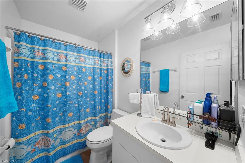 Bathroom featuring a built-in vanity with an integrated sink, a large wall-mounted mirror, and a wall-mounted light fixture with clear glass shades