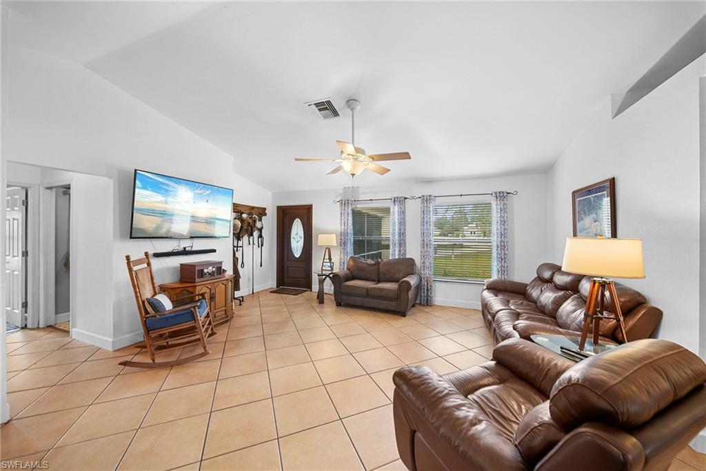 Spacious living area featuring diagonal tile flooring, a vaulted ceiling, and ample natural light through multiple windows