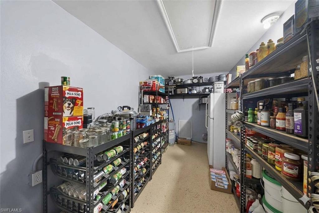 Spacious pantry featuring extensive metal shelving, light-colored walls, and a durable speckled floor