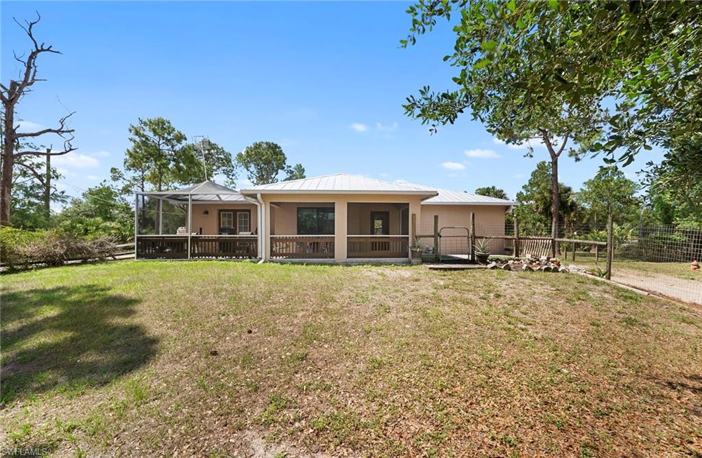 Rear exterior featuring a covered patio, screened lanai, wood fencing, and metal roof