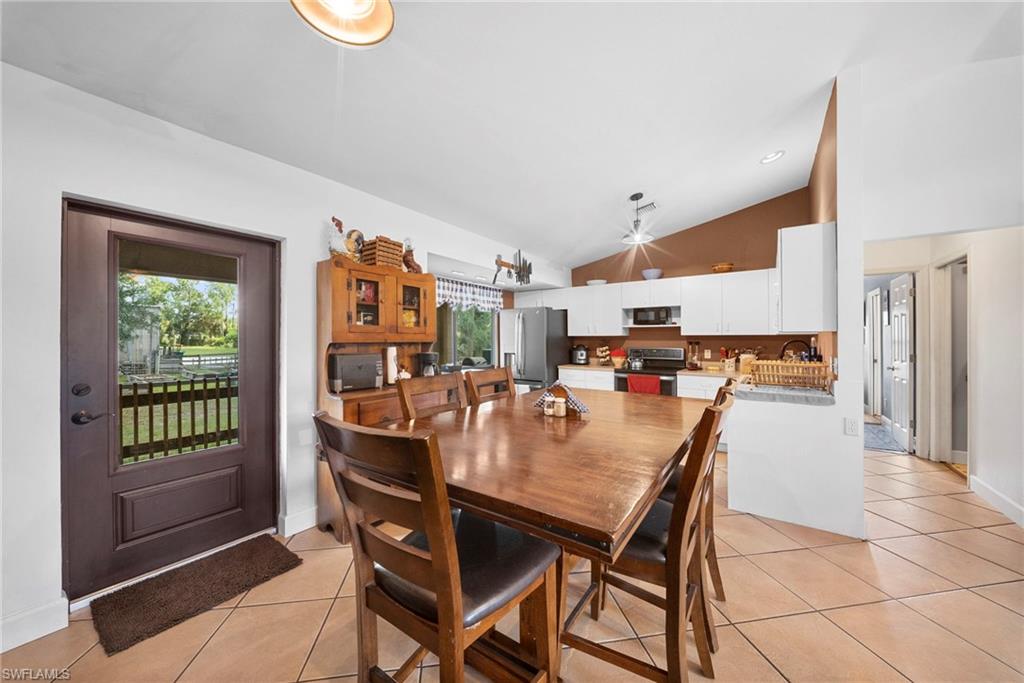 Spacious kitchen and dining area with vaulted ceilings and tile flooring