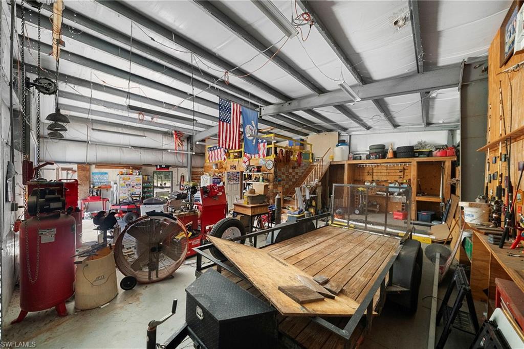 Spacious metal-frame interior featuring a high ceiling, visible structural beams, concrete flooring, and built-in wooden shelving