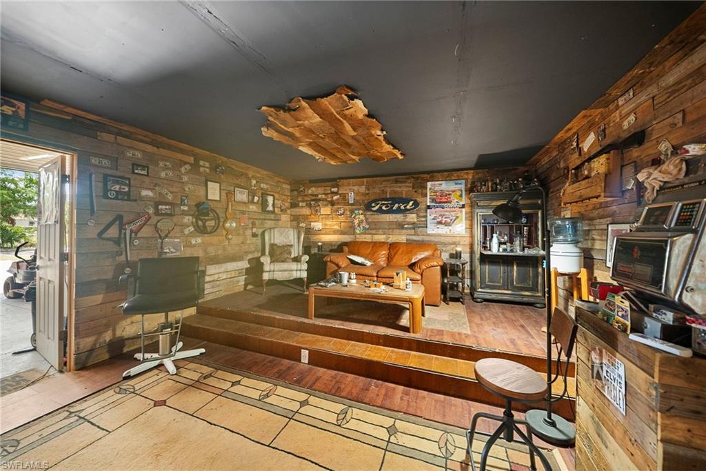Interior space featuring wood-finish wall paneling, a tiered wood-finish floor structure, and a dark ceiling