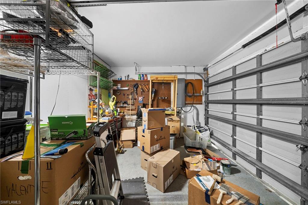 Garage space featuring an overhead door, built-in wall-mounted shelving, and a wall-mounted pegboard