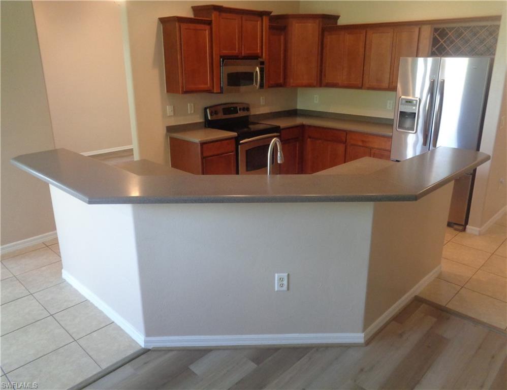 Kitchen with stainless steel appliances, light brown cabinetry, Corian countertops, and kitchen island
