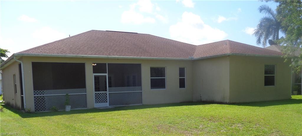 Back view of single-story home with a screened lanai, shingle roof, and stucco siding