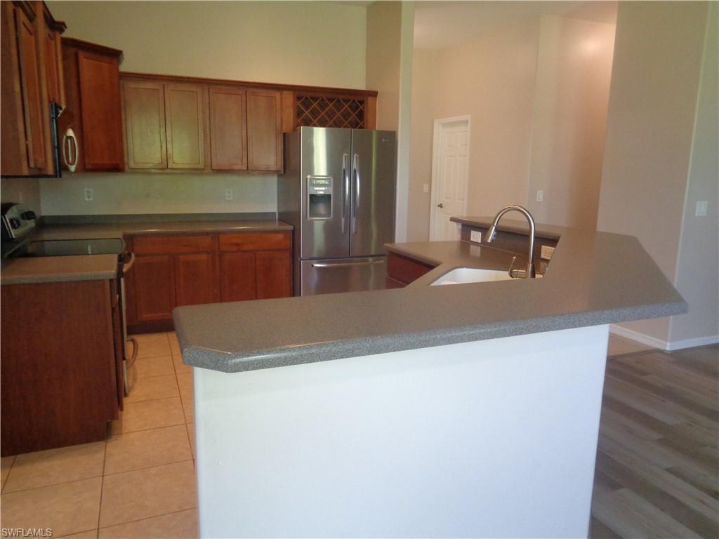 Kitchen with stainless steel appliances, light brown cabinetry, Corian countertops, and kitchen island