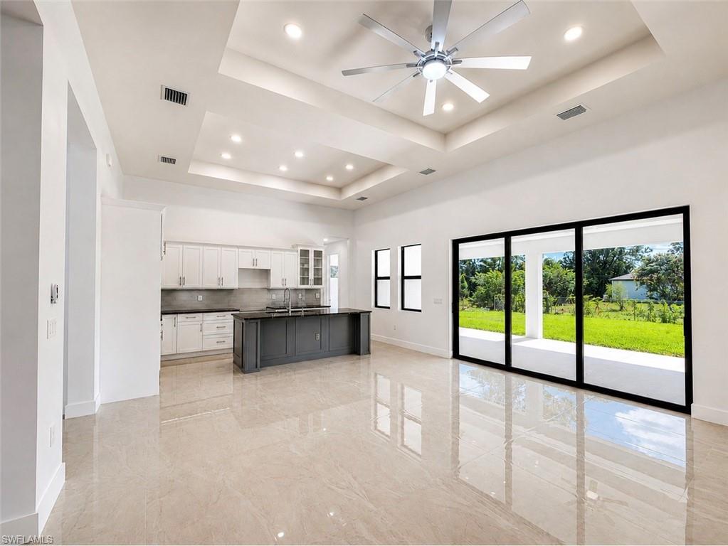 Open-concept living area featuring high ceilings with recessed lighting, an integrated ceiling fan, and large format polished tile flooring