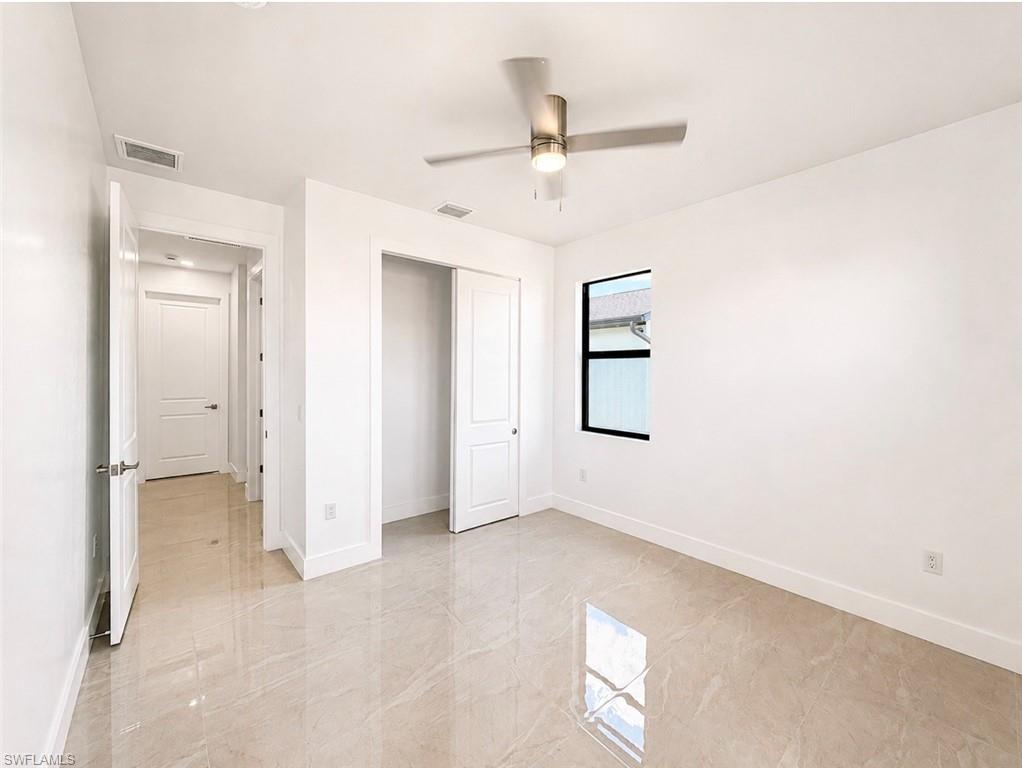 Spacious room featuring large format tile flooring, a contemporary ceiling fan with integrated lighting, and a window with black trim