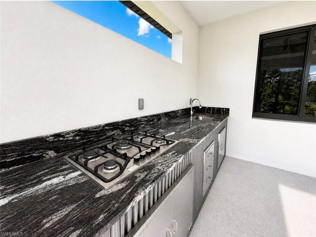 Outdoor kitchen featuring a built-in gas cooktop, sleek black stone countertop, and stainless steel cabinetry