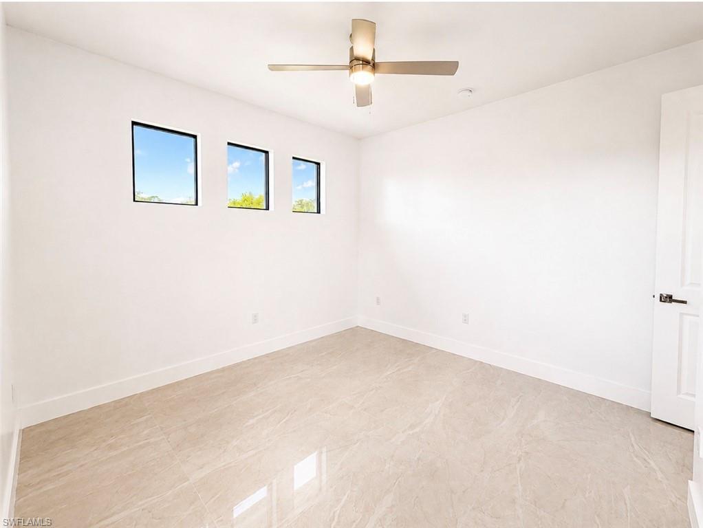 Room featuring light-toned tile flooring, three square windows with dark frames, and a modern ceiling fan with integrated lighting