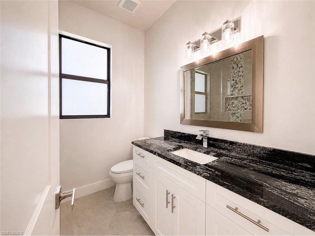 Vanity featuring a dark stone countertop with integrated sink and chrome faucet