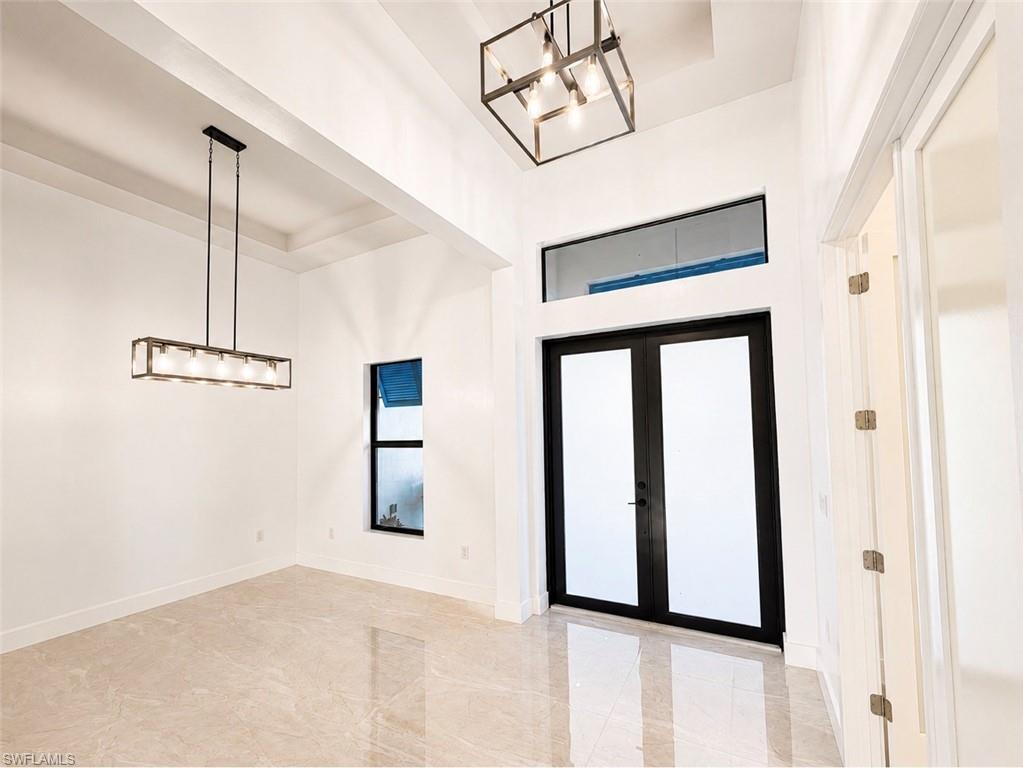 Foyer featuring a double-door entry with transom window, vaulted ceilings, and large format polished tile flooring