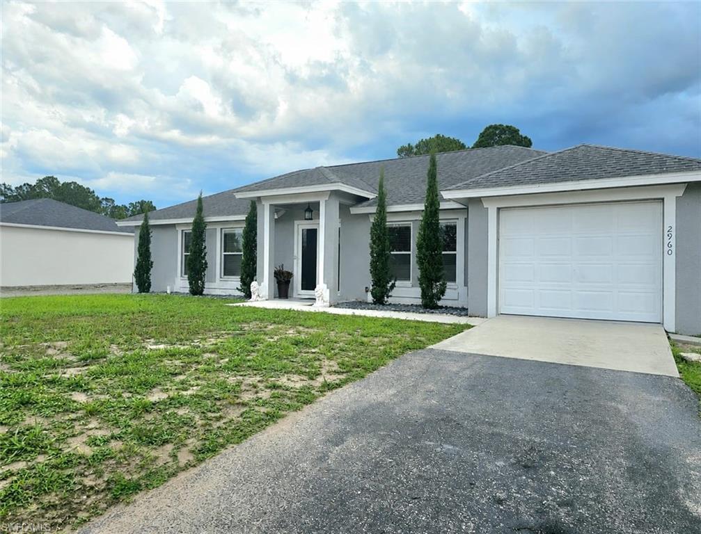 Contemporary single-story residence with a light gray stucco exterior and a dark shingle roof