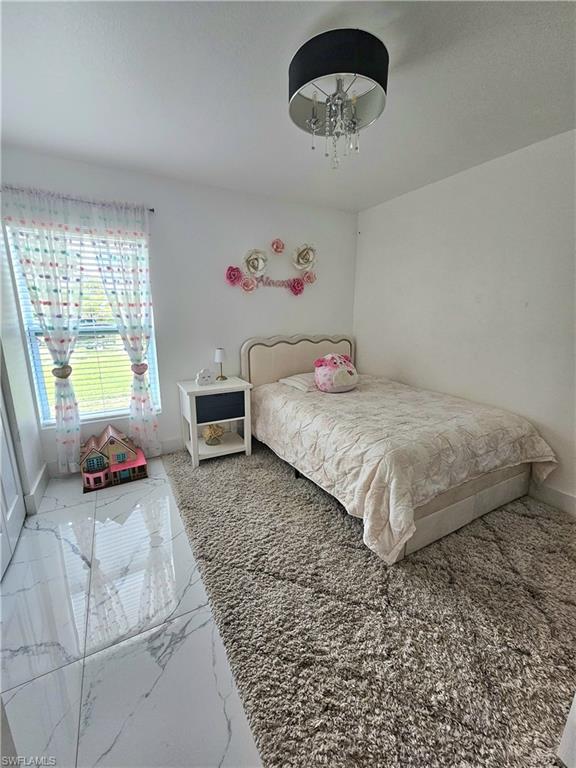 Bright guest room featuring large format tile flooring and a plush area rug