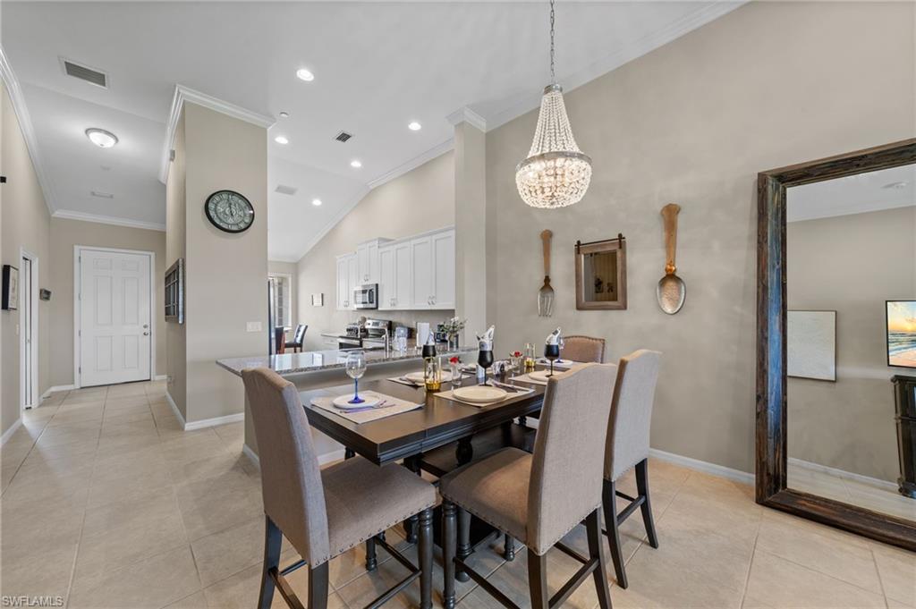Dining area with a crystal chandelier, tile flooring, and a breakfast bar overlooking the kitchen