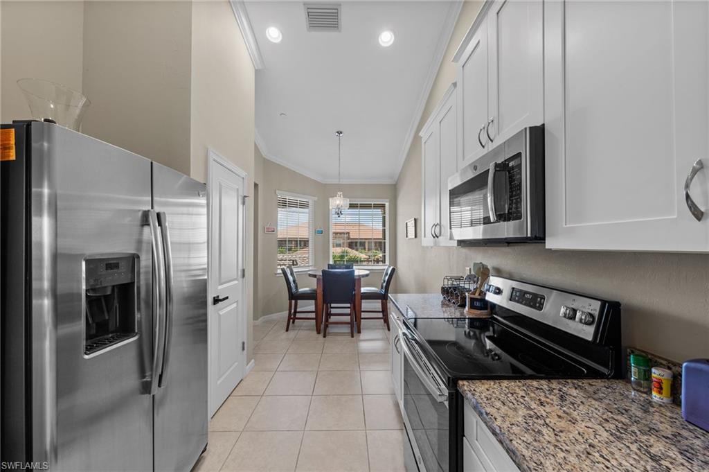 Kitchen featuring stainless steel appliances, white cabinetry, granite-style countertops, and tile flooring