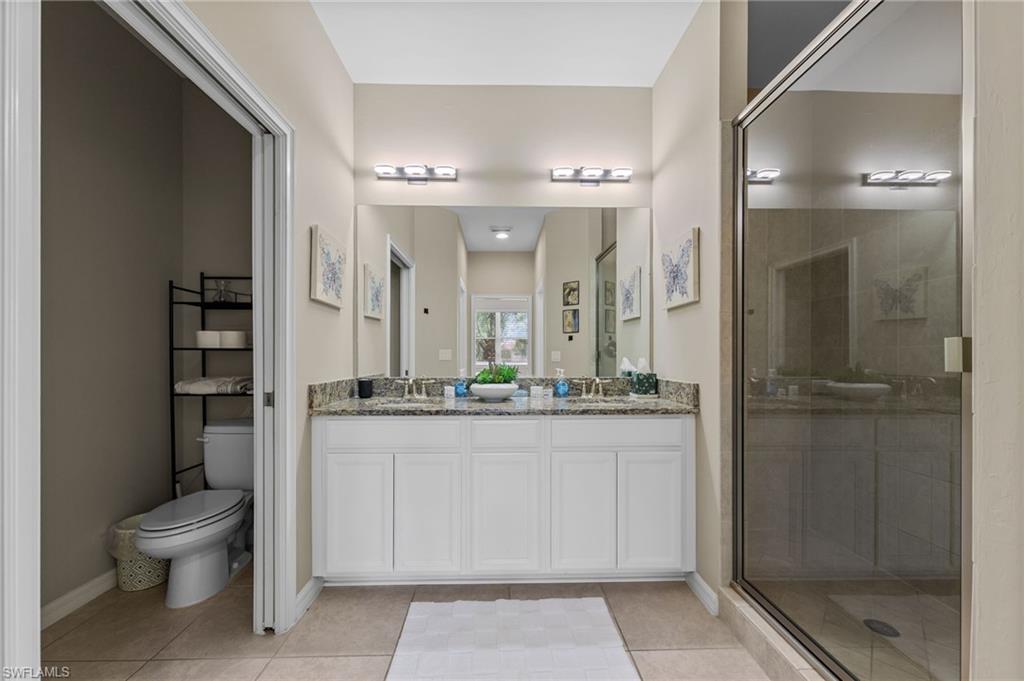 Bathroom featuring a dual vanity with white cabinetry, granite countertops, and two undermount sinks