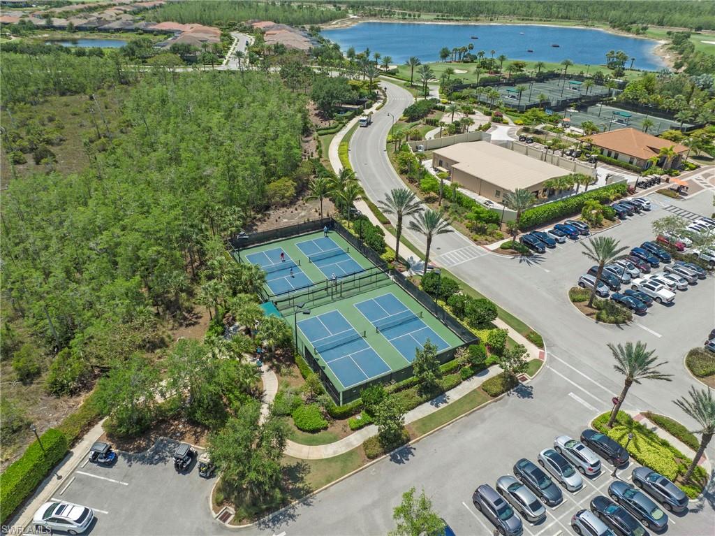 Aerial perspective showcasing multiple tennis courts, a lake, and surrounding natural landscaping