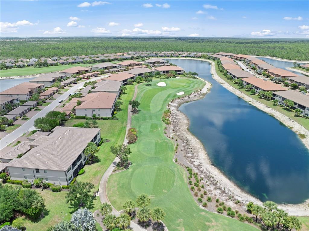 Aerial perspective showcasing a residential community with tile-roofed buildings, a prominent golf course, and a large body of water