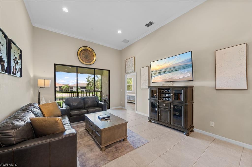 Spacious living area featuring high vaulted ceilings, recessed lighting, crown molding, and large format tile flooring