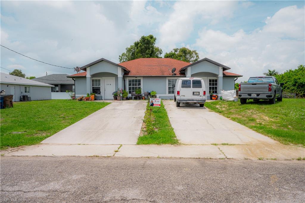 Duplex property featuring a light blue exterior, individual entryways, and two concrete driveways