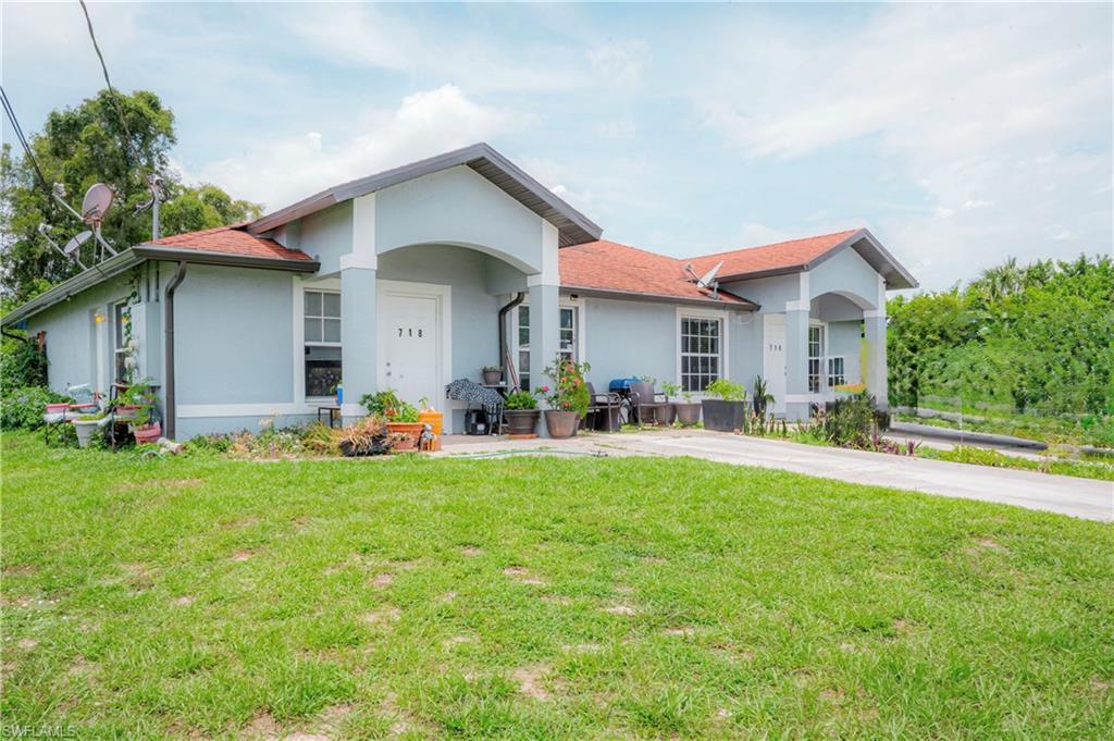 Duplex property featuring a light blue exterior, individual entryways, red tile roofing, and a concrete driveway