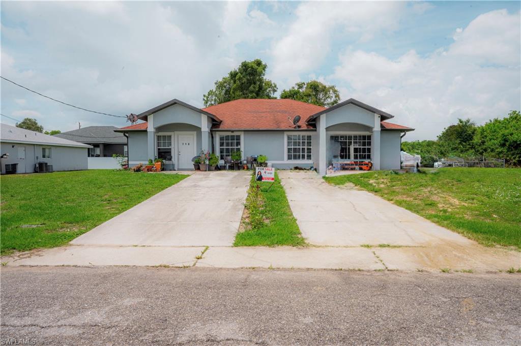 Duplex property featuring a light blue exterior with white trim, red shingle roofing, and two separate concrete driveways